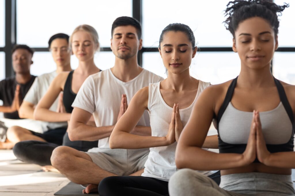 Mind Harmony. Group of young sporty yoga lovers meditating together in studio