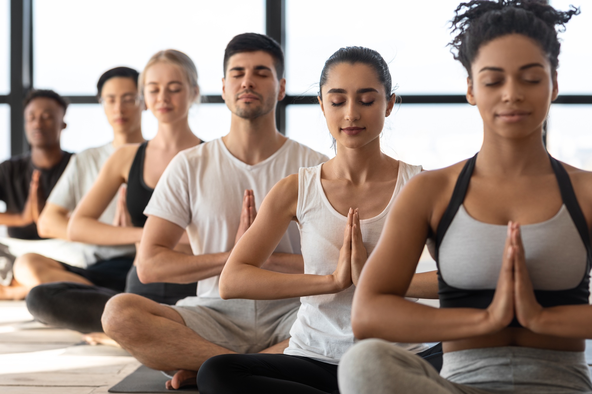 Mind Harmony. Group of young sporty yoga lovers meditating together in studio