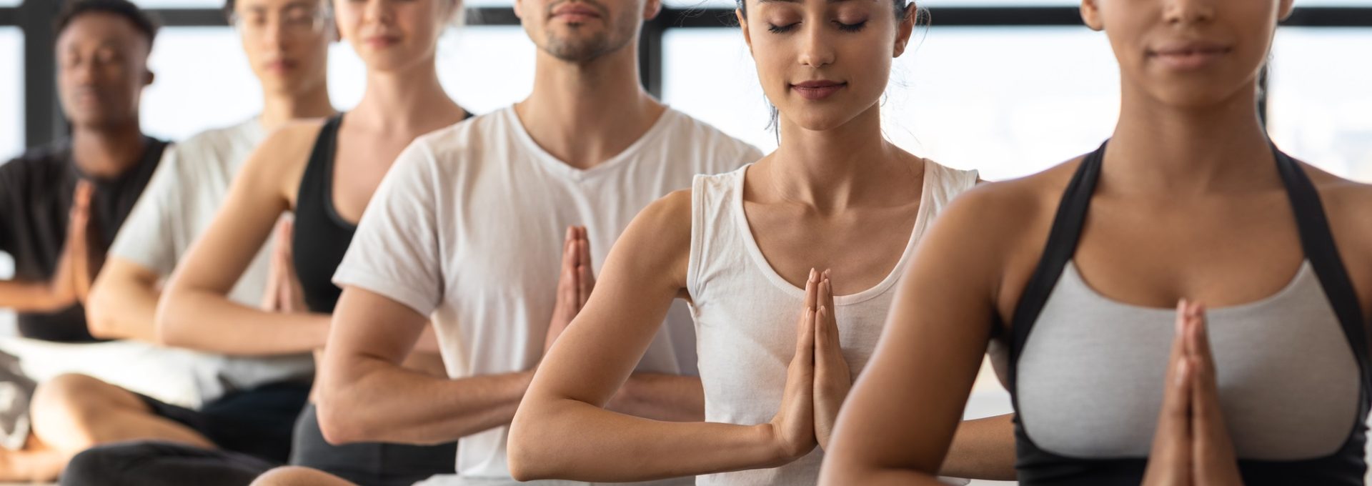Mind Harmony. Group of young sporty yoga lovers meditating together in studio
